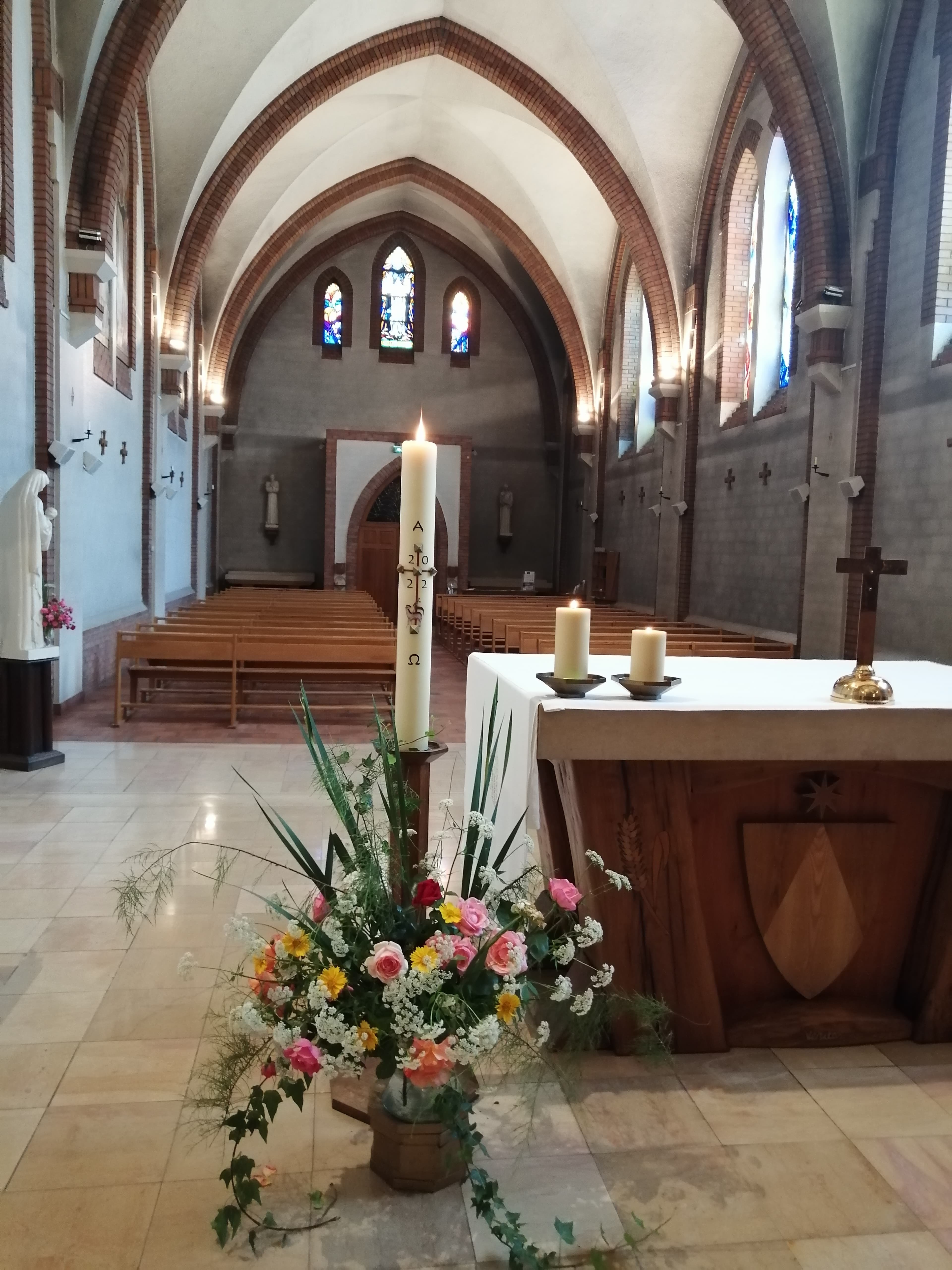 La nef de la chapelle du monastère, fleurie, avec le cierge pascal